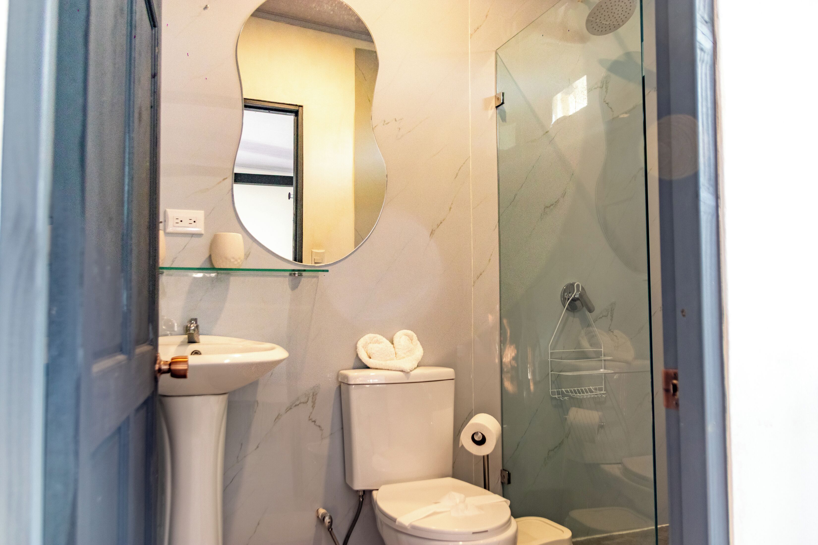 Un baño con inodoro, lavamanos y cabina de ducha de vidrio.