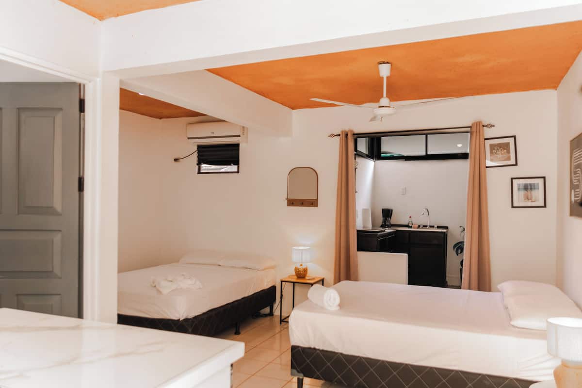 Habitación de hotel con dos camas, un escritorio, un espejo y un ventilador de techo.