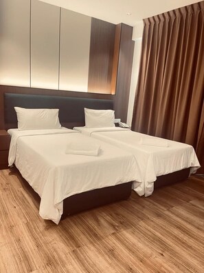 Une chambre d’hôtel moderne avec un grand lit, un plancher en bois et une tête de lit sombre.