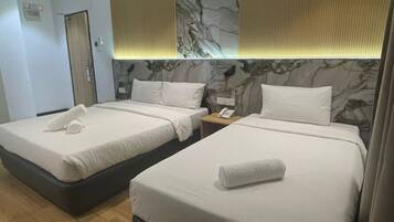 A hotel room with two beds, a marble headboard, a wooden floor, and a nightstand with a phone.