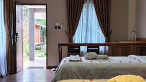 A hotel room with a bed, a desk, a window with curtains, and a door leading outside. - Thong's Inn - KNO Kualanamu Transit Hotel (Medan)