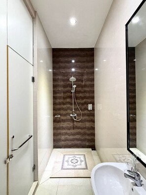 Een moderne badkamer met een douche, een wastafel en een spiegel.