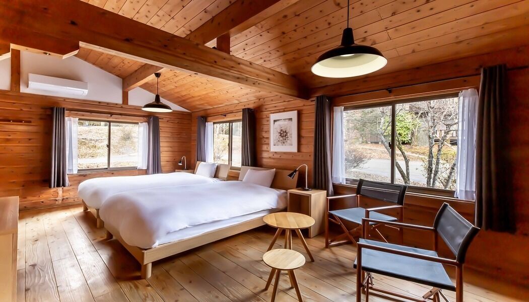 Quarto de cabana de madeira com uma cama grande, uma escrivaninha e uma cadeira.