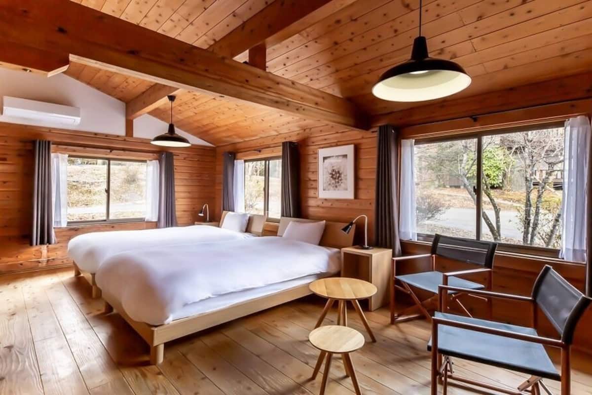 Un dormitorio de cabaña de madera con una cama grande, un escritorio y una silla.