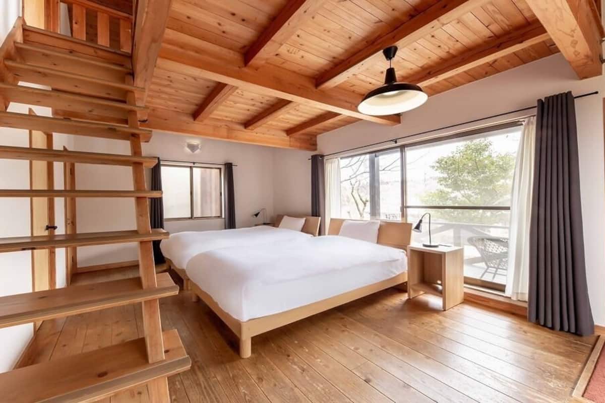 Un dormitorio con una escalera de madera, una cama grande, una mesita de noche y una ventana con vistas.