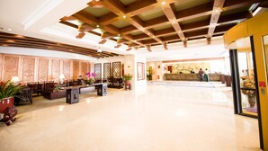 Um hall amplo com teto alto, vigas de madeira e balcão de recepção.
