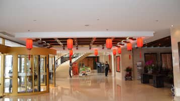 A hotel lobby with a glass partition, red lanterns, a staircase, and a reception desk.