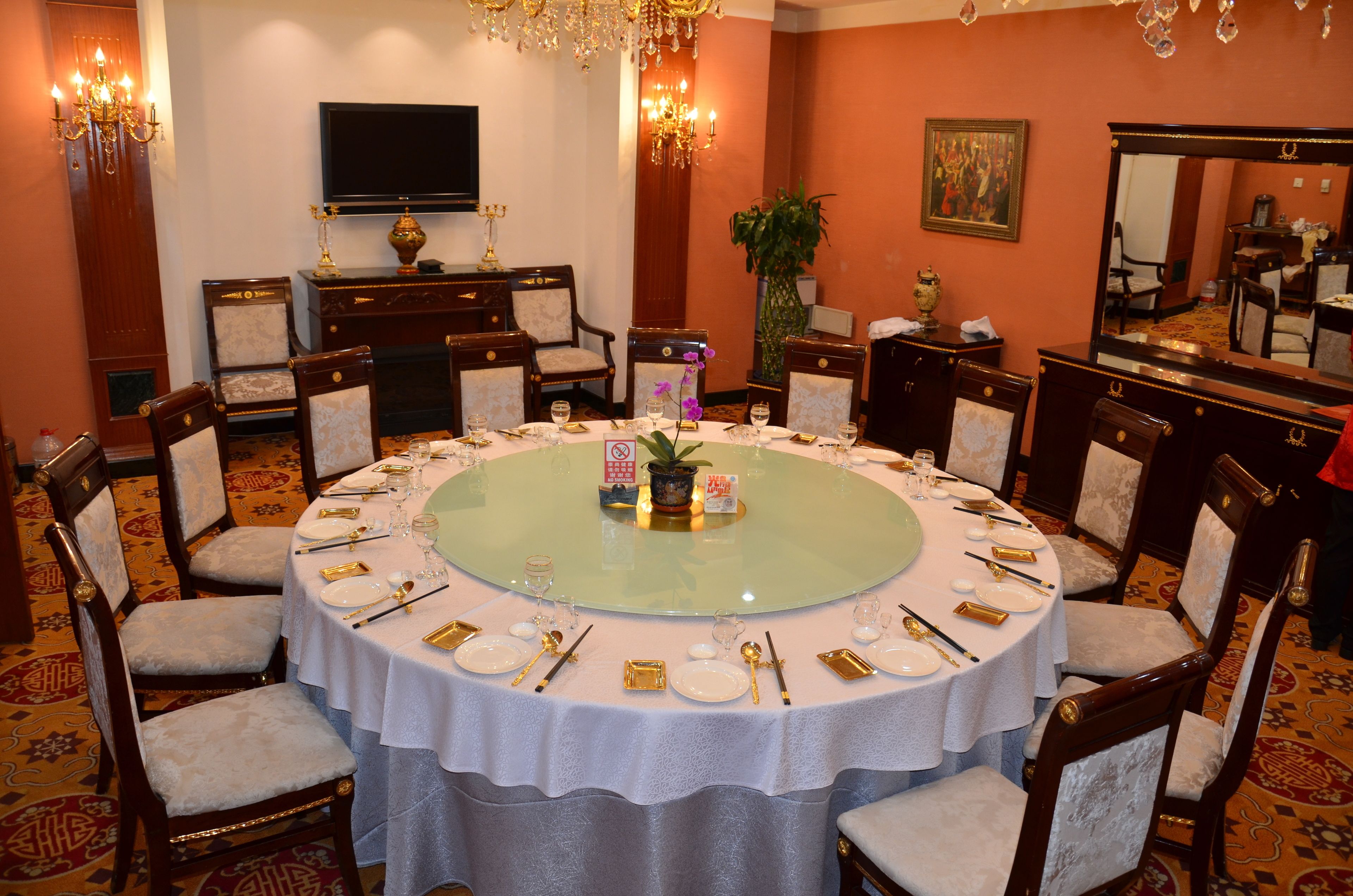 A round dining table with white tablecloth, surrounded by wooden chairs with cushioned seats.