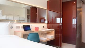 Une chambre d’hôtel moderne équipée d’un lit, d’un bureau avec un ordinateur portable, d’un lavabo et d’une armoire.