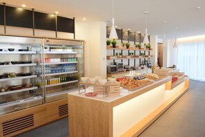 A modern breakfast bar with refrigerated drinks, shelves with condiments, and a variety of breakfast items.