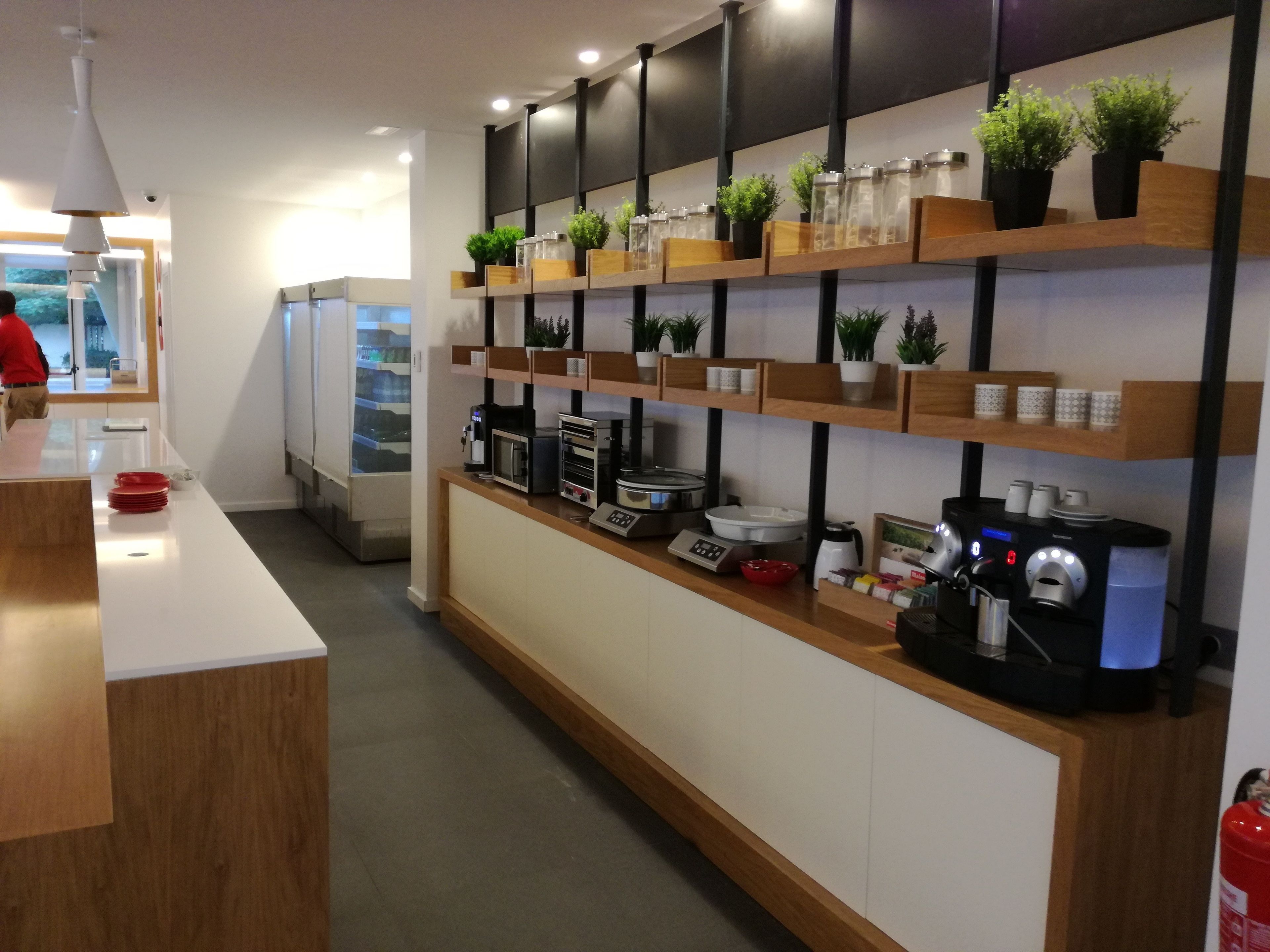 Una cocina moderna con estantes de madera, una cafetera y un refrigerador.