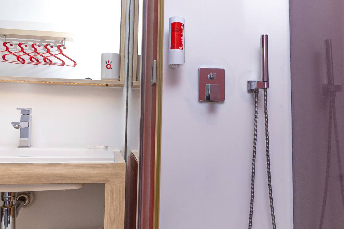 Une salle de bain moderne avec une douche à parois de verre, un meuble-lavabo en bois, un miroir et un porte-serviettes.
