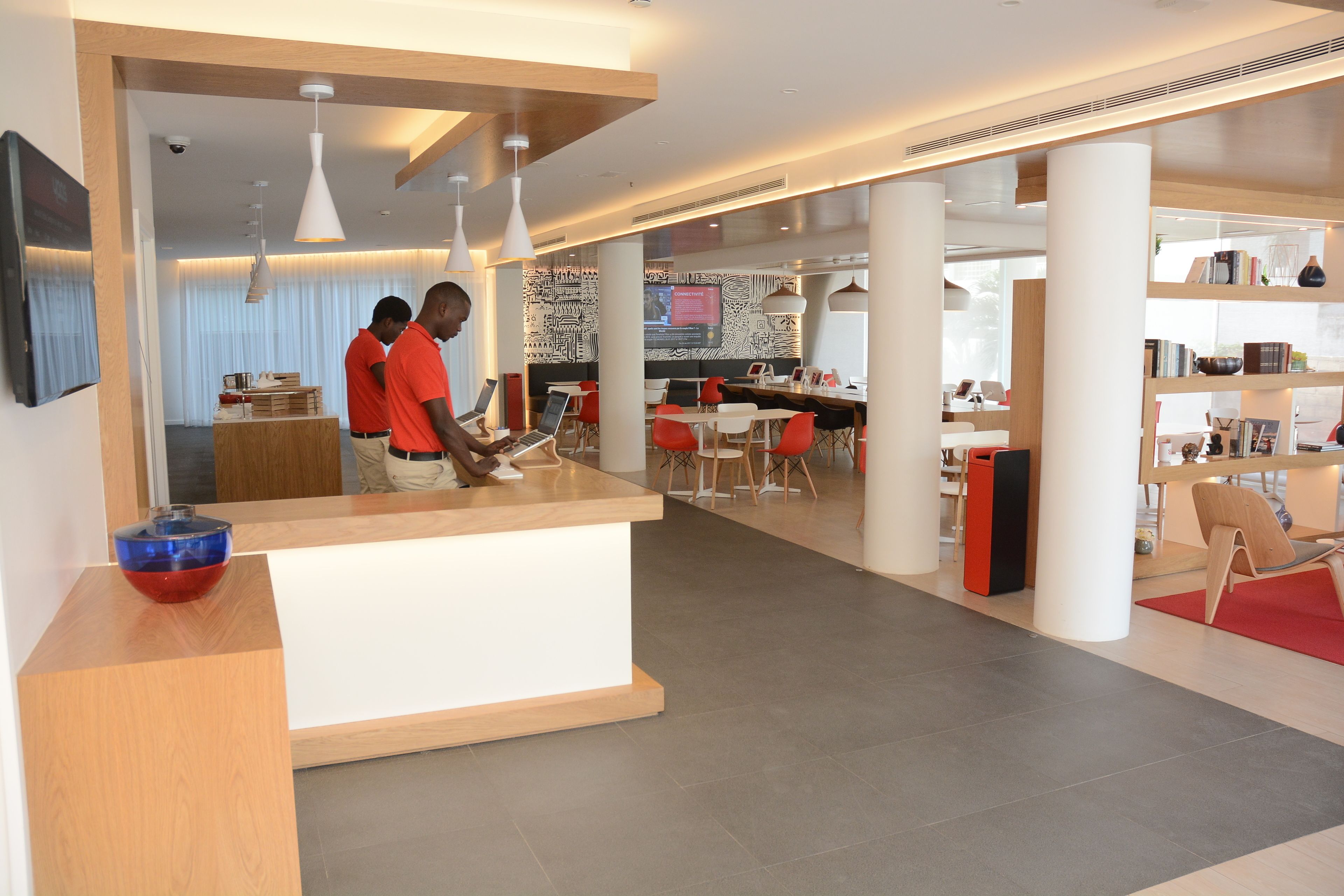 Un hall d’hôtel moderne comprenant un comptoir d’accueil, un espace salon et un bar.