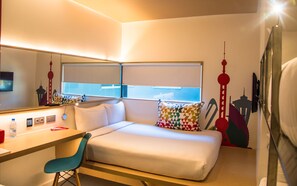 A modern hotel room with a bed, a desk, and a chair. There is a window with blinds, a mirror, and a television. - Yaas Hotel Dakar Almadies (Dakar)