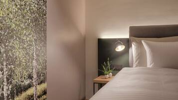 A hotel room with a bed, a nightstand, a wall-mounted lamp, and a textured wall.