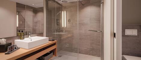 A modern bathroom with a glass-enclosed shower, a white sink, and a wooden vanity.