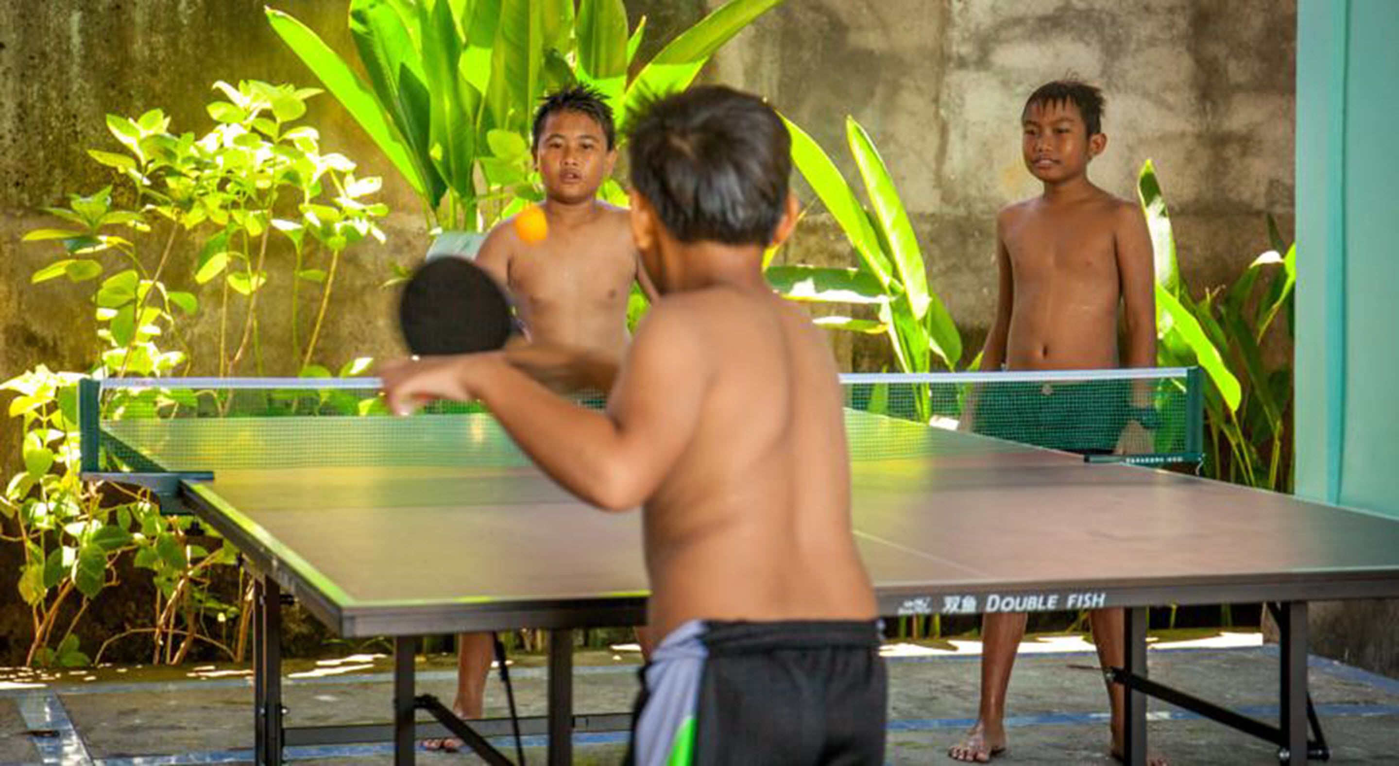 A table tennis table with a net in an outdoor setting with greenery.