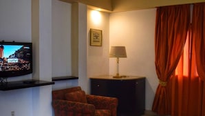 Una sala de estar con televisión de pantalla plana, una mesa redonda, un sofá y una lámpara.