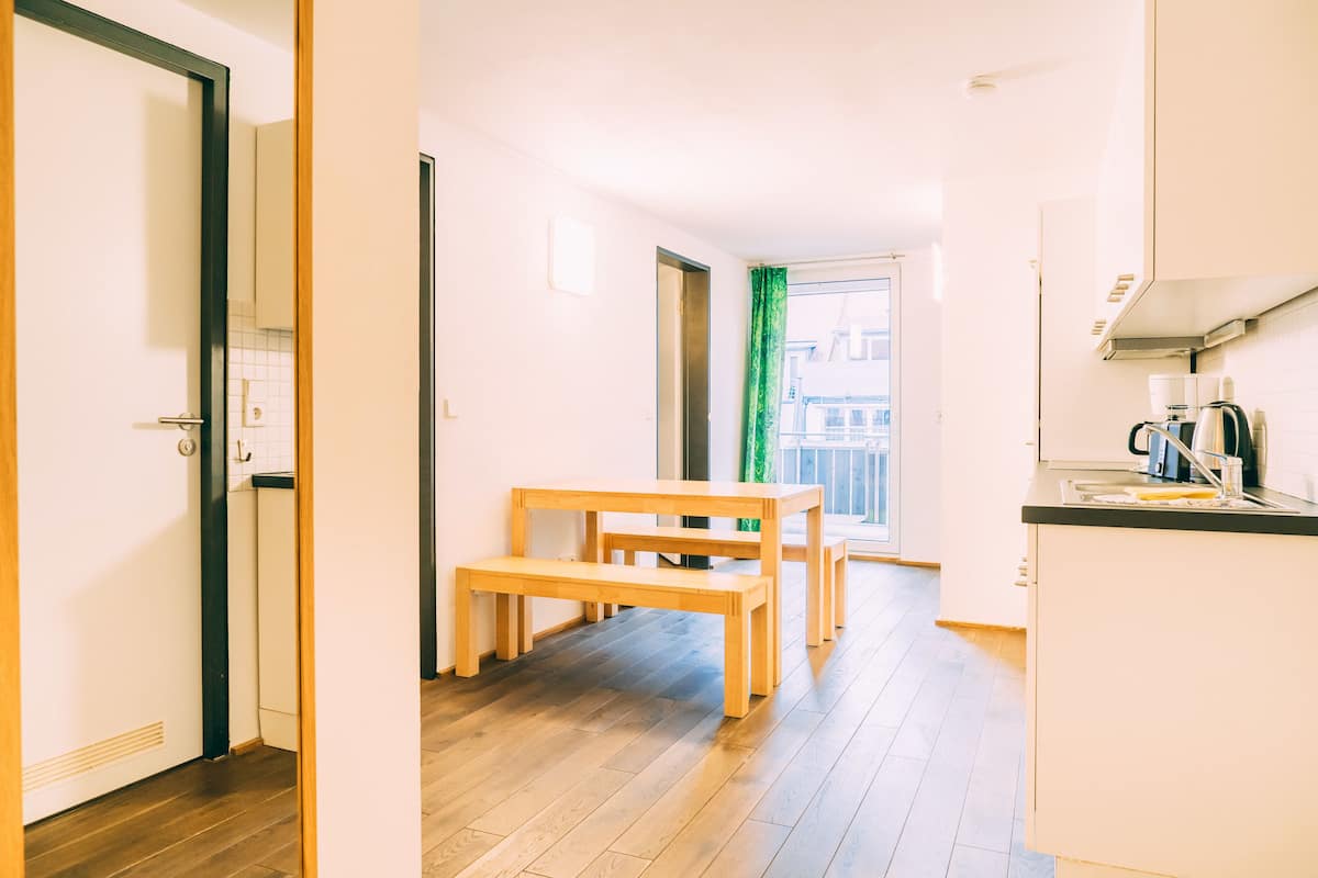 Eine moderne Küche mit Holzboden, einem Essbereich mit einer Bank und Blick ins Freie durch ein Fenster.