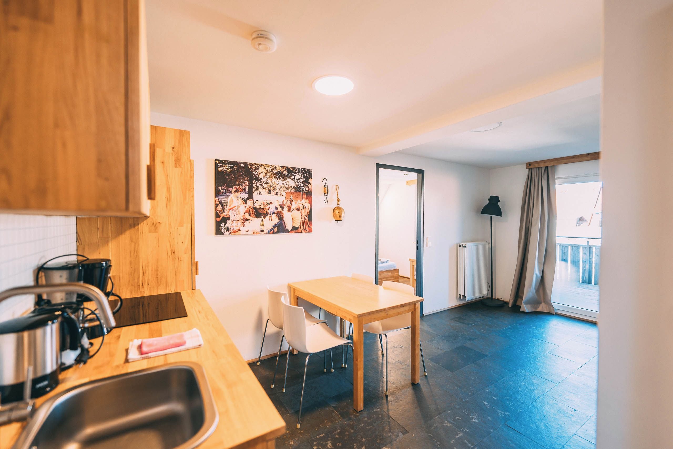 A compact kitchen with a sink, stove, and a dining area with a table and chairs.