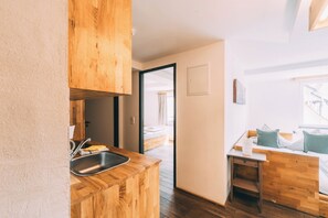 A compact kitchen with a wooden countertop, a sink, and a door leading to a bedroom. - Stadthaus Gut Hügle (Ravensburg)