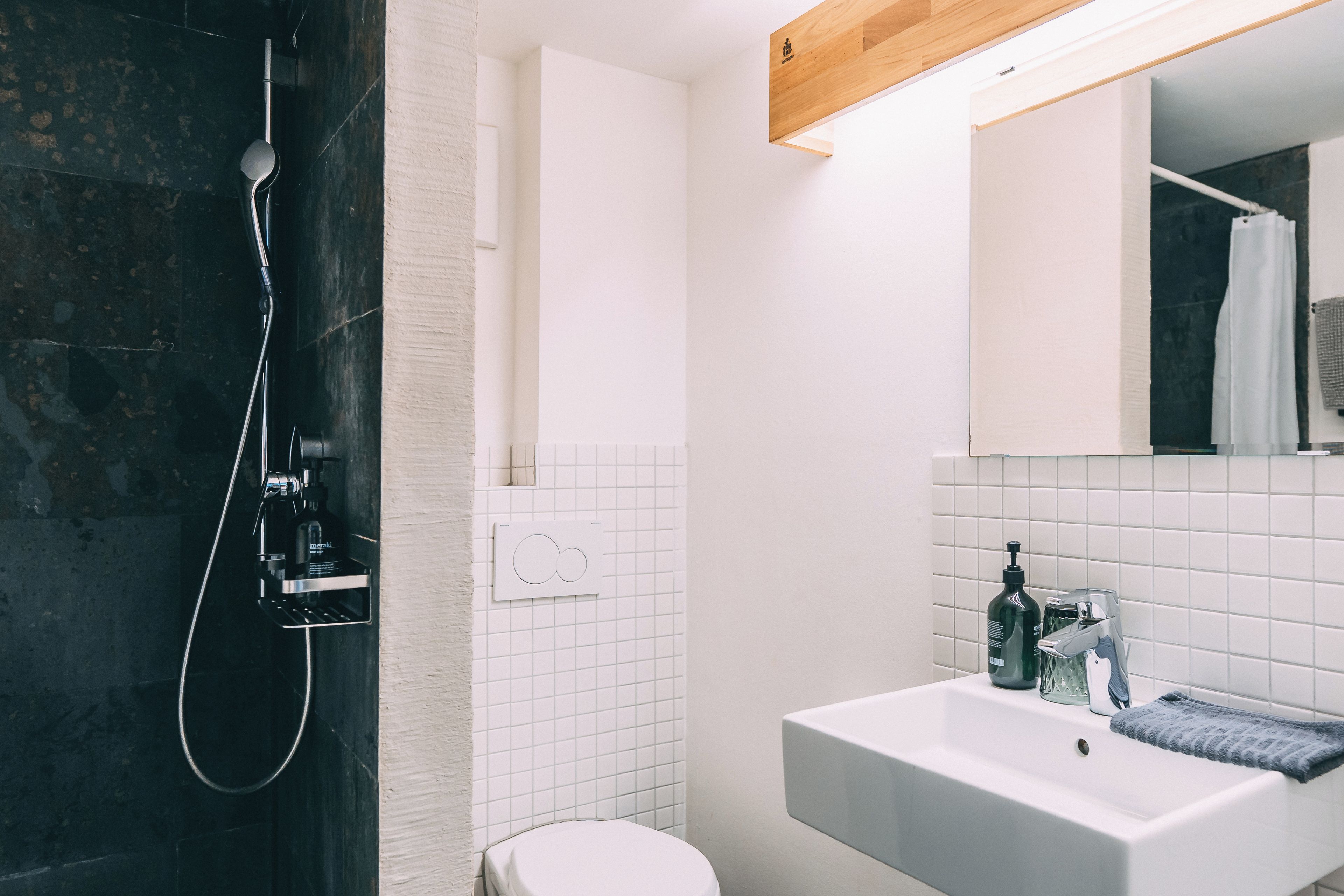 A modern bathroom with a shower, toilet, sink, and mirror.