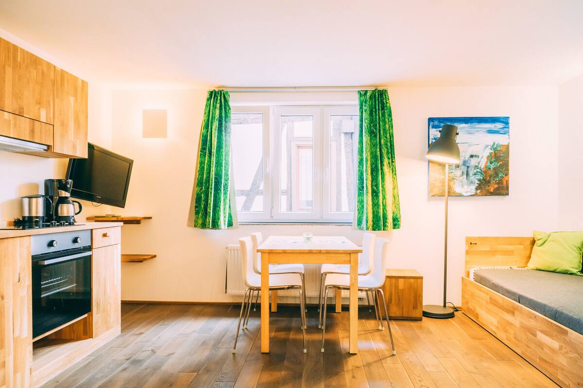 Eine kleine Küche mit Essbereich, einer Couch und einem Bild an der Wand.