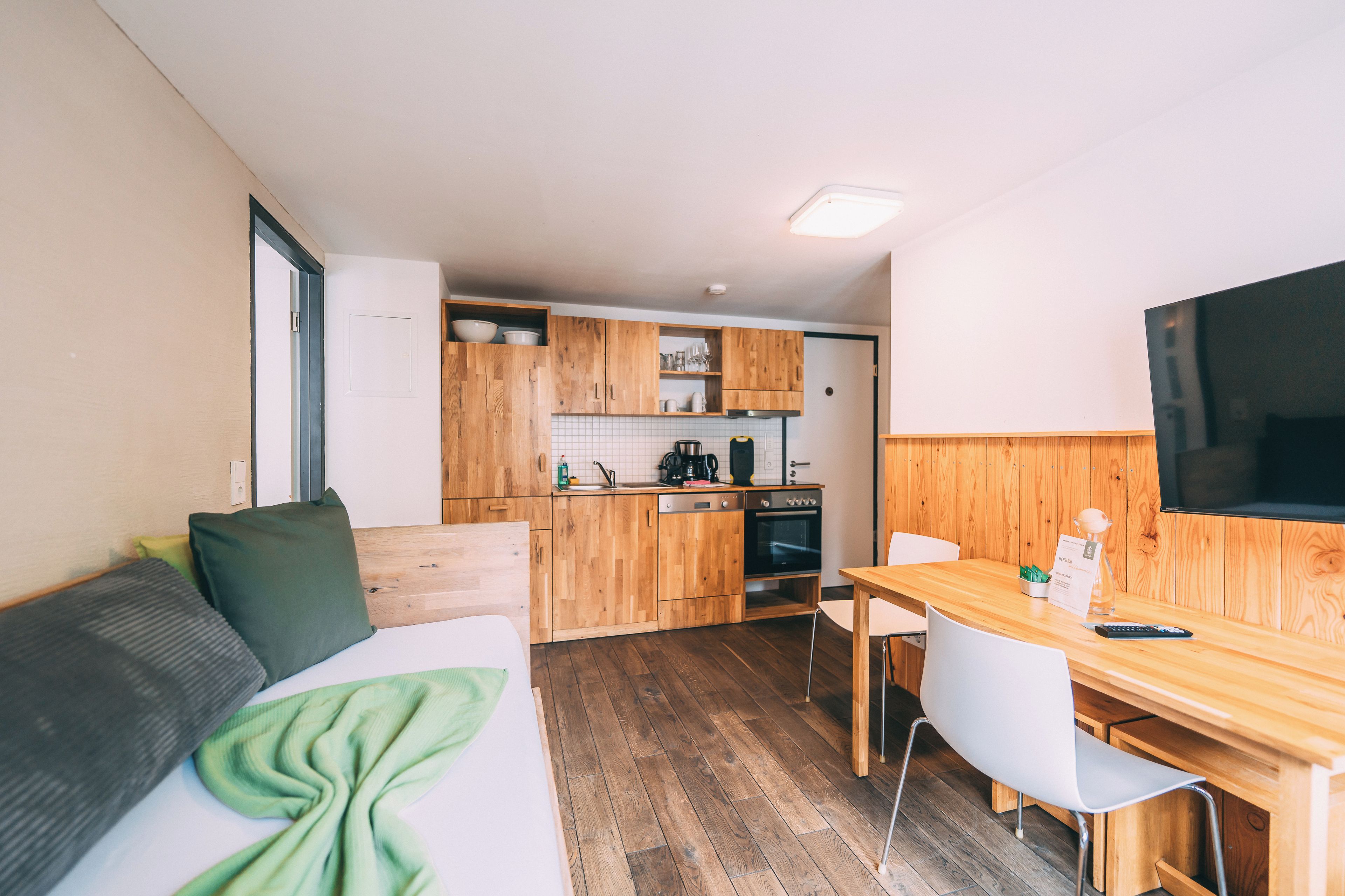 Une petite cuisine équipée avec des meubles en bois, un four encastré et un coin repas comprenant une table et des chaises.