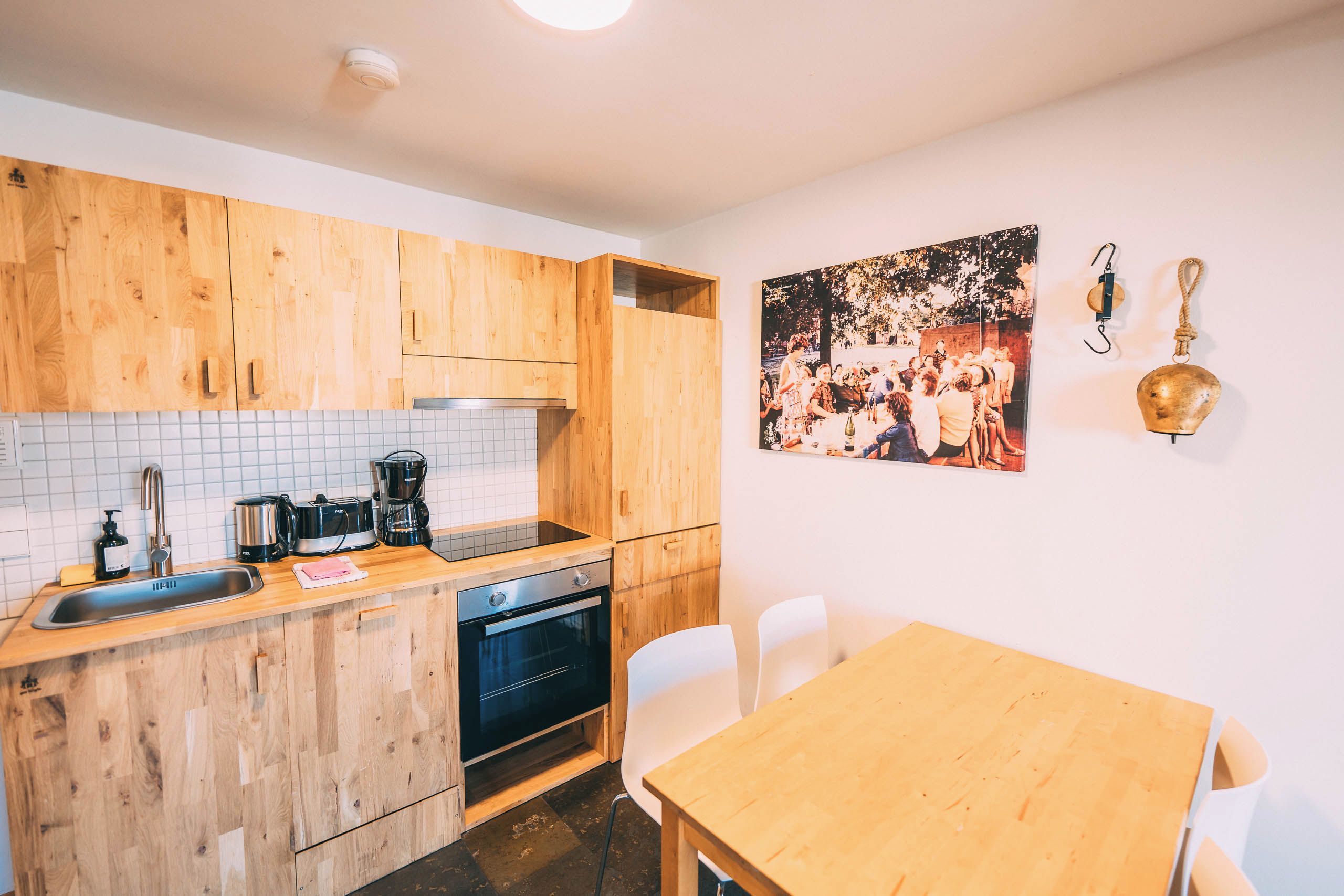 Una cocina con armarios de madera, salpicadero de azulejos, un lavamanos, estufa y una mesa de comedor con sillas.