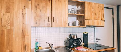 Eine Küche mit Holzschränken, einer Edelstahl-Spüle, einer Kaffeemaschine und einer Mikrowelle.