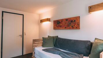 A bedroom with a bed, a painting, and a wall-mounted light fixture.