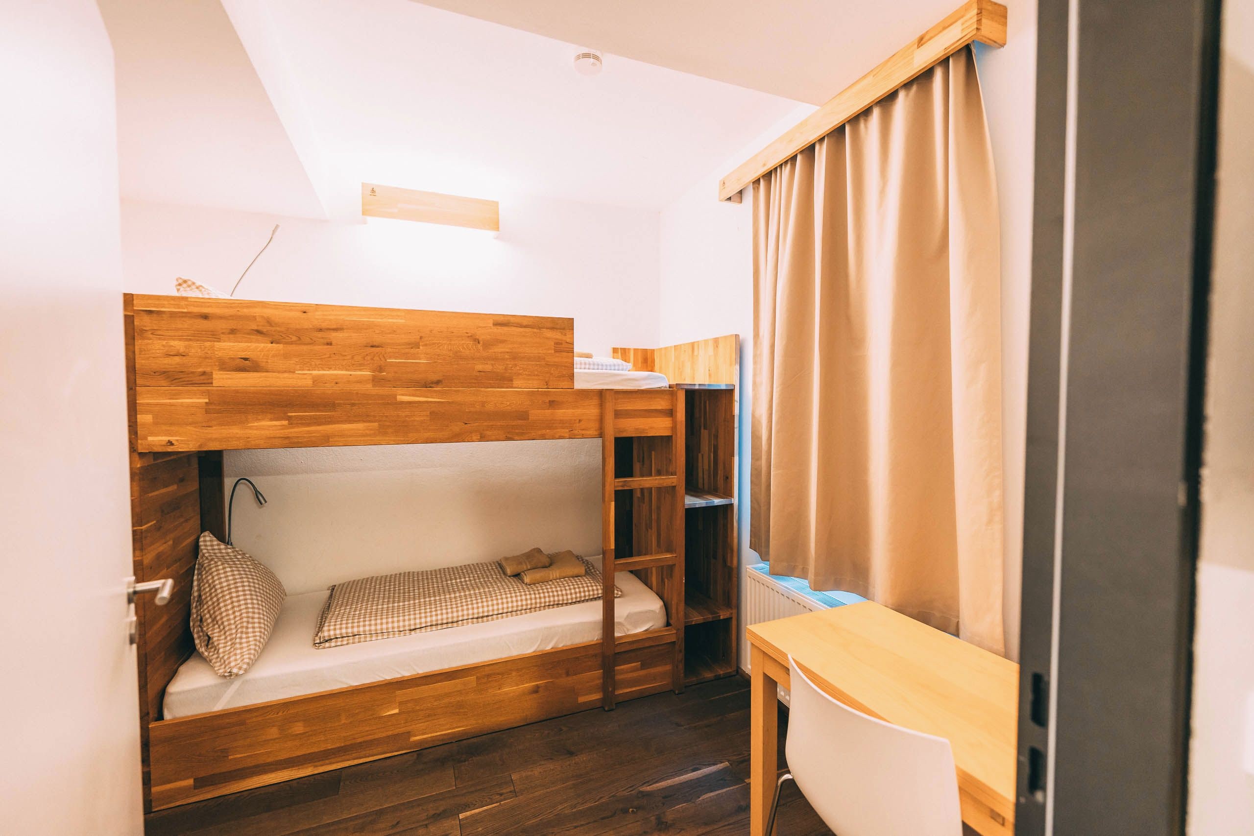 A compact room with a bunk bed, a small desk, and a chair.