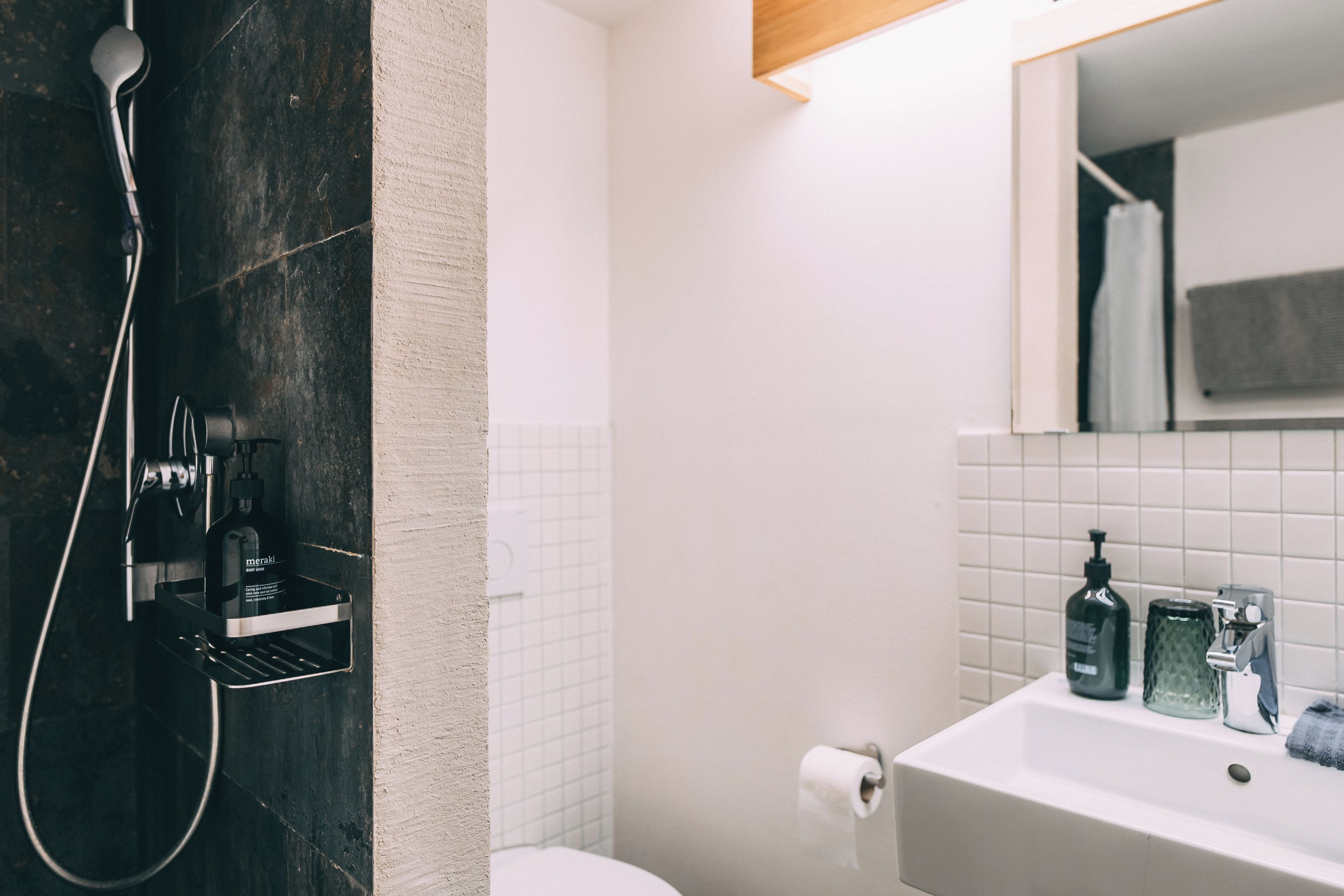 Een badkamer met een douche, een wastafel en een spiegel.
