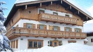 Ein mehrstöckiges Chalet mit Holzbalkonen und einem mit Schnee bedeckten Dach.