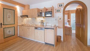 Eine kompakte Küche mit Holzschränken, einem Geschirrspüler, einer Mikrowelle und einer Kaffeemaschine.
