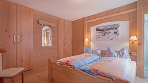 Ein Schlafzimmer mit Holzboden, einem Bett, einem Sessel und einem Spiegel.