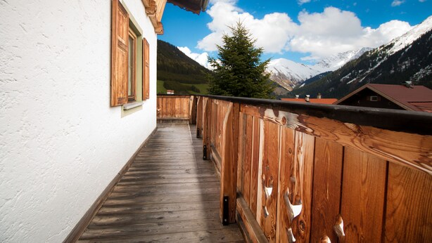 Ein hölzerner Balkon mit Blick auf schneebedeckte Berge und einen klaren Himmel.