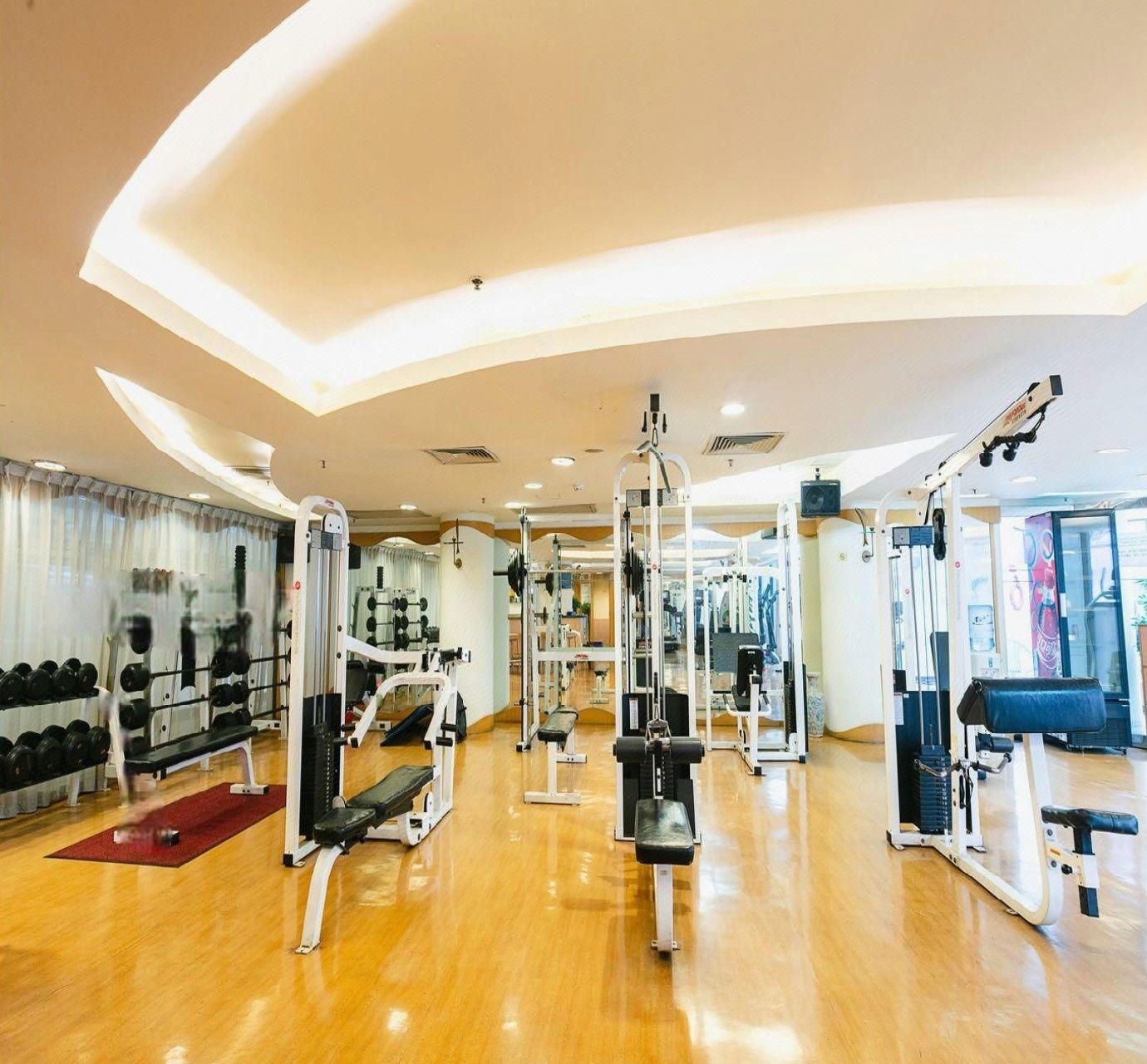 Une salle de sport équipée de divers appareils d’exercice, d’un banc et d’haltères.