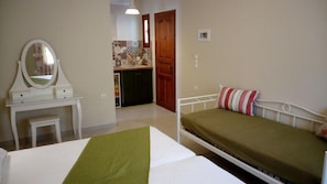 Ein Schlafzimmer mit Bett, Nachttisch, Spiegel und einem kleinen Hocker.
