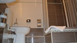 Une salle de bain équipée de toilettes, d’une douche et d’un porte-serviettes.