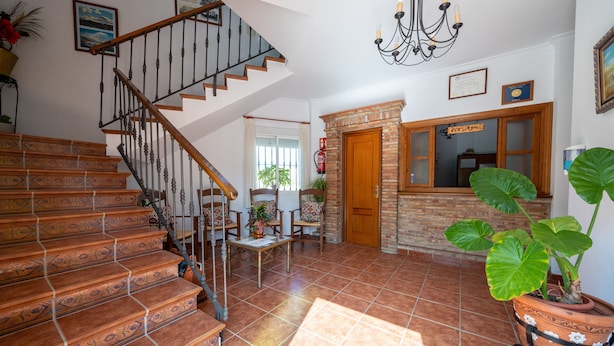 A spacious living area with a staircase, a fireplace, and a dining table. - Hostal Vista a la Sierra (Valle de Abdalagis)