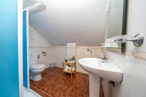 A small bathroom with a toilet, a sink, and a mirror. - Hostal Vista a la Sierra (Valle de Abdalagis)
