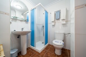 A bathroom with a glass-enclosed shower, a sink, and a toilet. - Hostal Vista a la Sierra (Valle de Abdalagis)