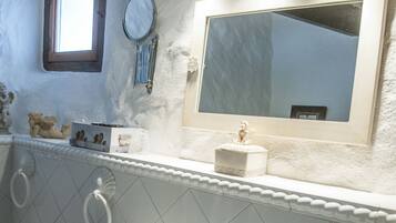 Un baño con lavamanos blanco, un espejo y una ventana.
