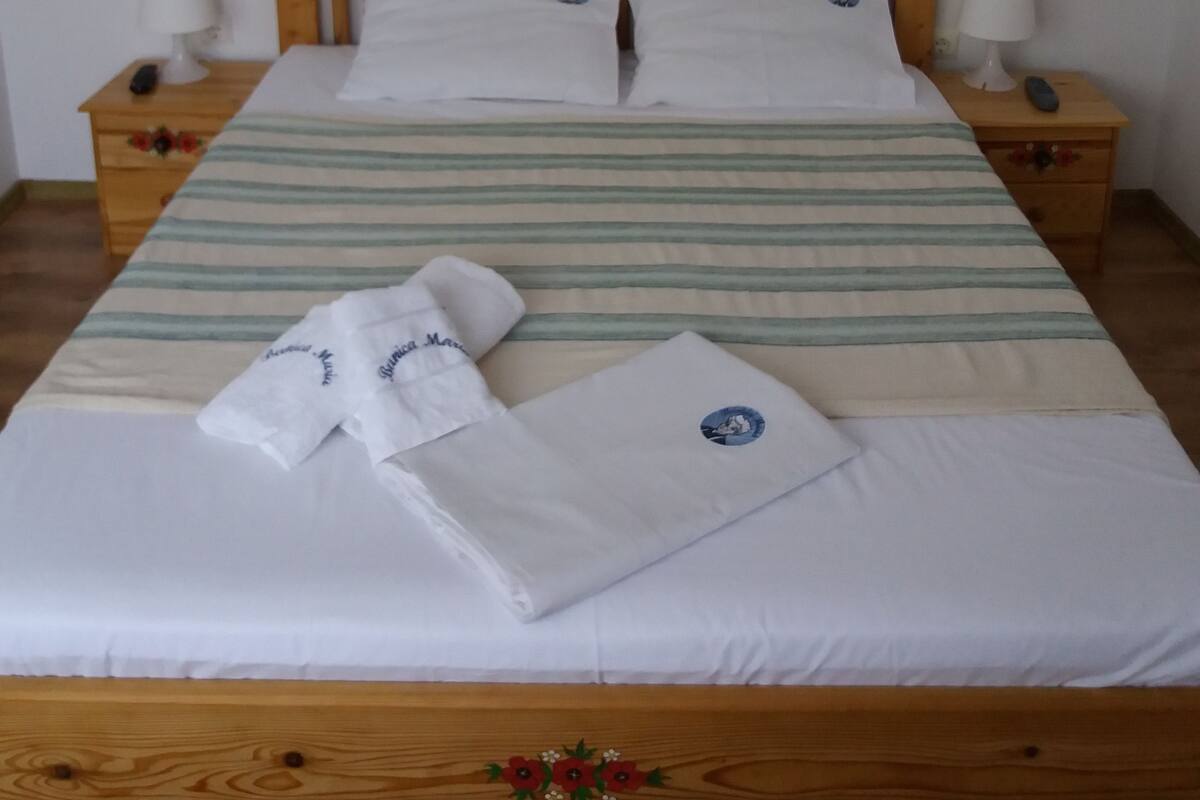 A neatly made bed with striped bedding, two bedside tables with lamps, and three wall decorations.