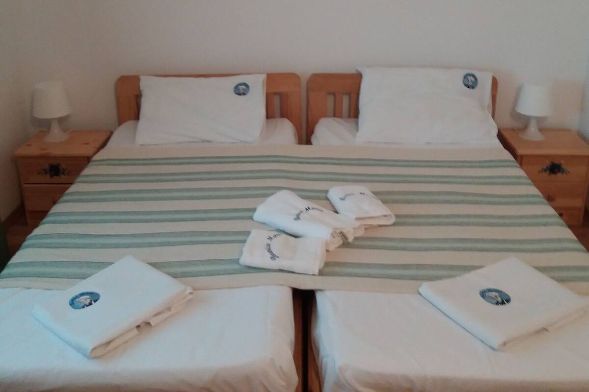 A double bed with a striped bedspread and two pillows, flanked by wooden nightstands with lamps.