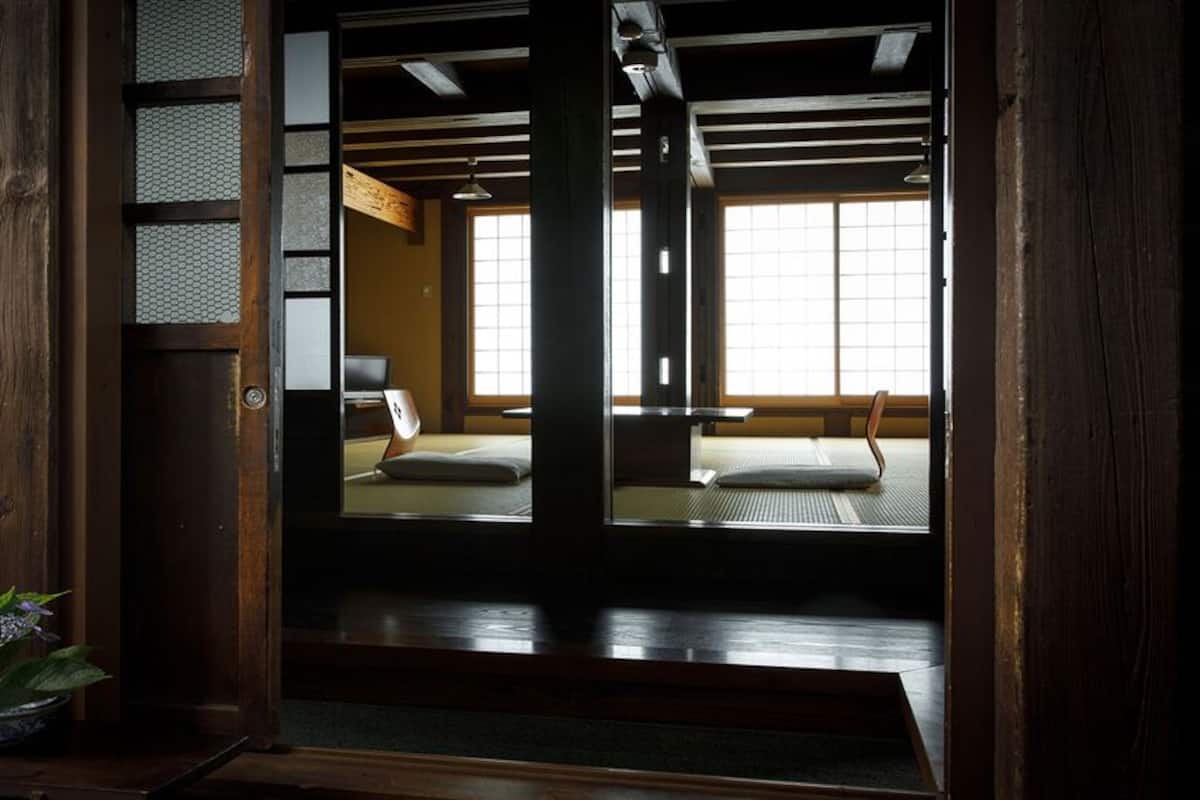 Una habitación japonesa tradicional con suelo de tatami, un panel shoji y una planta en maceta.