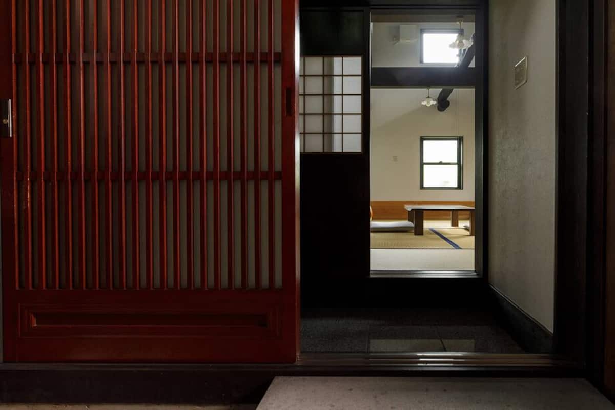 Una habitación japonesa tradicional con suelo de tatami, una mesa de madera baja y una puerta corredera.