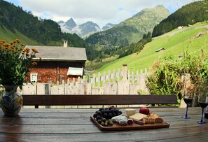 A wooden table with a cheese board, grapes, and wine glasses. - Gabrielenhaus (Wassen)
