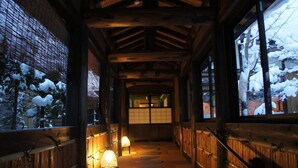Een houten gang met tatami matten die leidt naar een traditionele Japanse kamer.